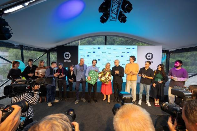 Finalisté Future Frames 2025: Robert Chvátal (uprostřed), generální ředitel skupiny Allwyn, předává symbolický kufr loňskému vítězi Simonu Schneckenburgerovi